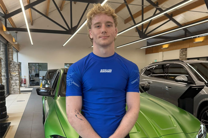 Sam Holladay standing with BMW car in South Lakes Showroom