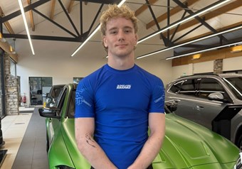 Sam Holladay standing with BMW car in South Lakes Showroom