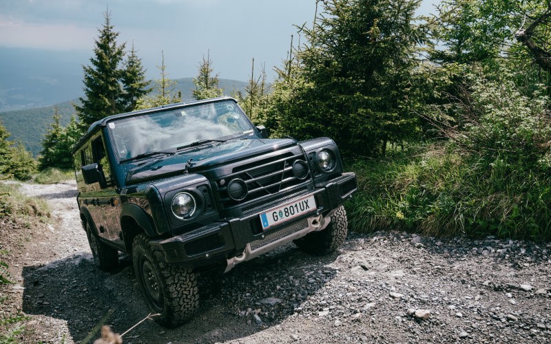 the INEOS Grenadier driving off road through woodland