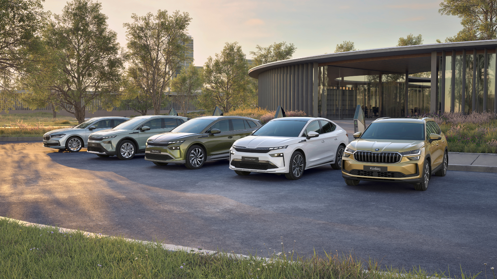 Four Škoda vehicles — including the Enyaq, Enyaq Coupé, and Kodiaq — displayed together on a forecourt outside a modern curved architectural building, surrounded by mature trees in a parkland setting at golden hour.
