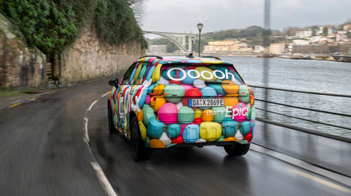 Skoda Epiq driving with the sea and seaside city in background