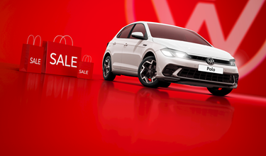 A white Volkswagen Polo against a bold red background, surrounded by red sale shopping bags.