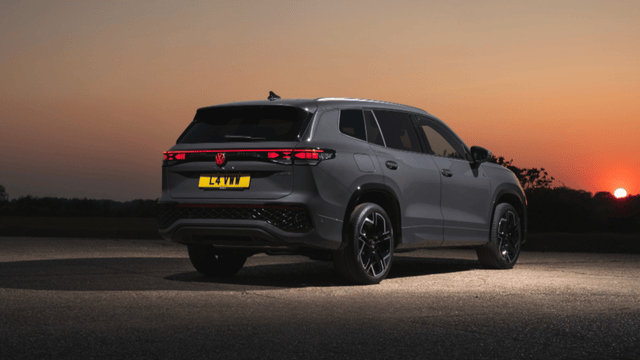 A dark silver Volkswagen Tiguan viewed from the rear in the dusk, with rear lights on